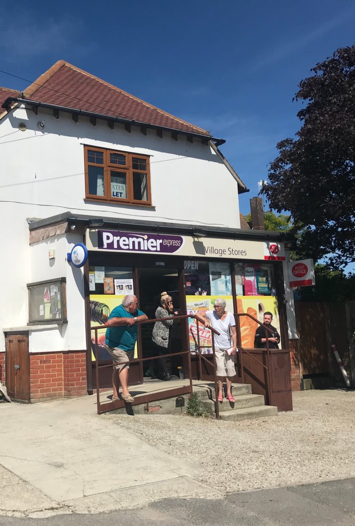 image of a Premier express village store with people outside. 